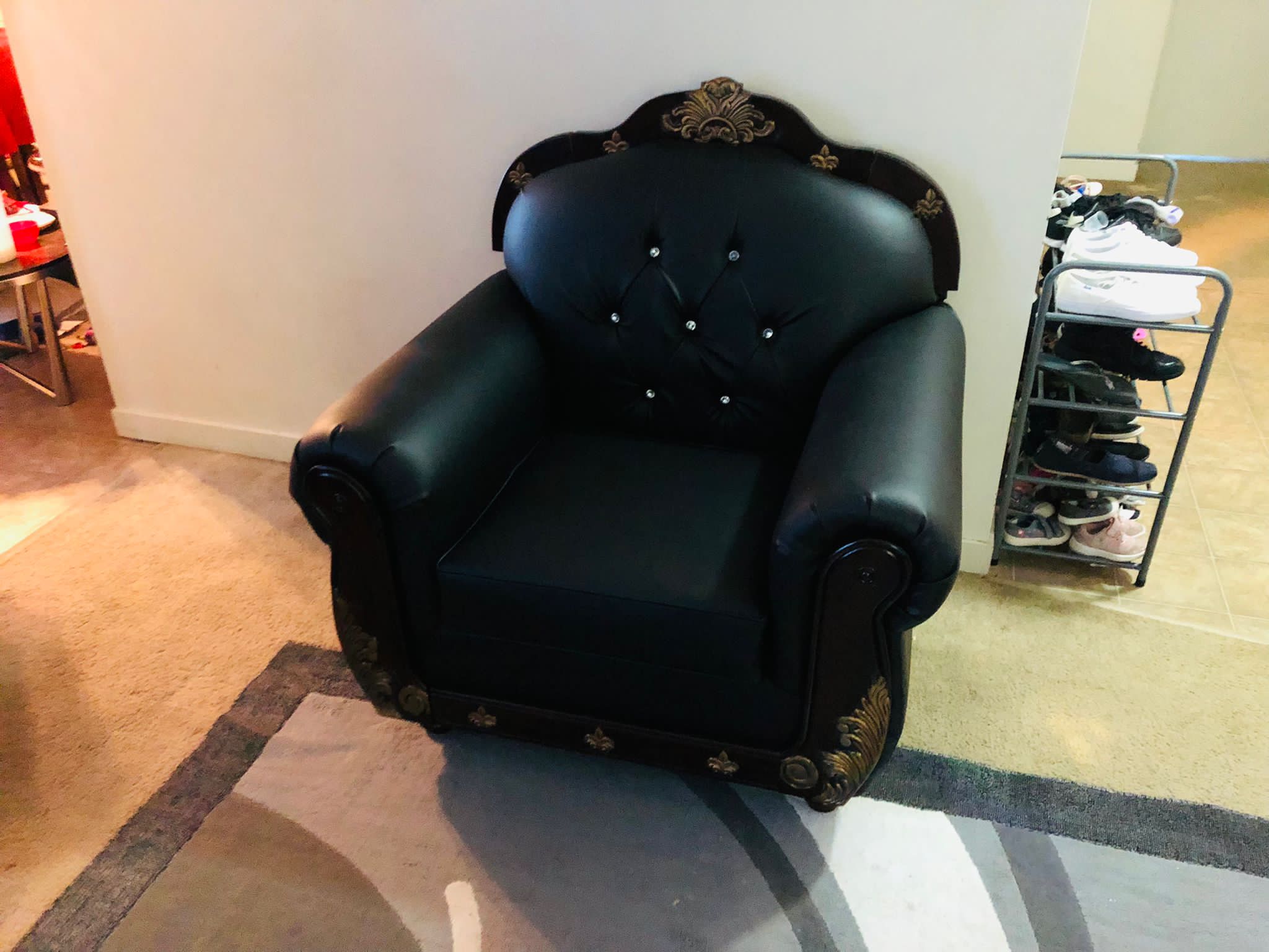 Black leather armchair with tufted back and gold decorative accents.